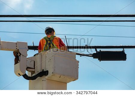 A Low Angle And Close Up Shot Of A Man At Work In An Aerial Work Platform, Awp, Wearing High Visibil