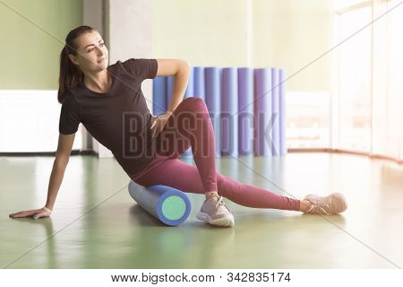Attractive Female Doing Foam Roller Exercise And Posing In Modern Bright Fitness Center