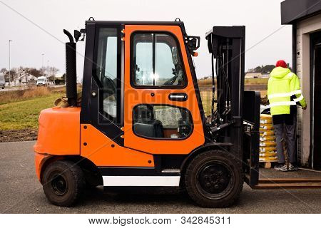 Reliable loader, forklift truck. A worker is ready to load pallets with a mini loader