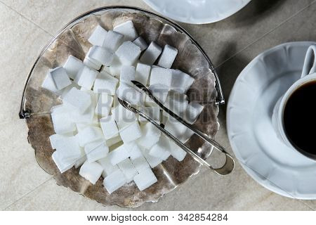 Sugar Cubes In Metal Vintage Sugar  Bowl With Sugar Tongs Top View.