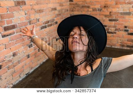 A Happy And Content Woman Is Seen Wearing A Large Brimmed Hat During A Mindful Yoga Routine, With Ey