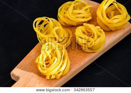 Pasta Alluovo, Tagliatelle Pasta, Round Balls Of Raw Pasta On The Wooden Cutting Board On Black Back