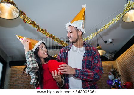 Man And Woman Snile And Holding Red Heart Pillow On Hand In The Party, Concept Of Love And Celebrate