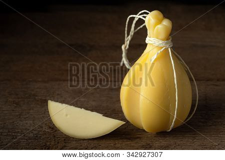 Head And Slice Of Typical Italian Cheese Caciocavallo On A Wooden Surface.