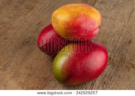 Three Ripe Mango Fruits On A Wooden Texture Background. Selective Focus.