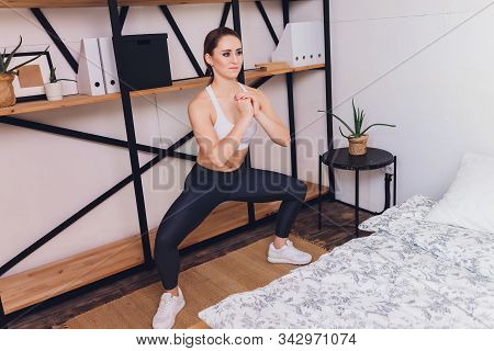 Attrctive Fitness Woman Doing Stretching Exercises At Home, As Part Of A Healthy Lifestyle Without G