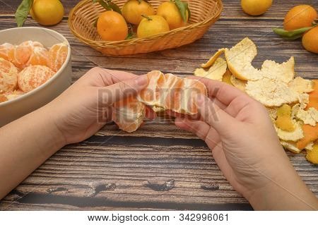 The Girls Hands Are Cleaning Tangerine, Tangerines On A Twig With Green Leaves, Peeled Tangerines In