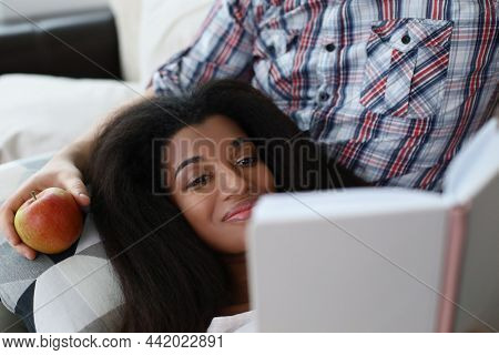 Portrait Of Latino American Young Woman Reading Interesting Book Laying On Fathers Lap. Smiling Fema