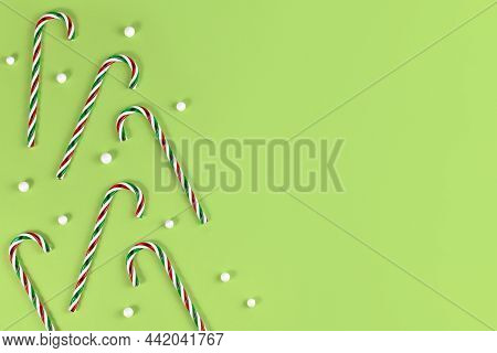 Striped Candy Cane Christmas Sweets With Snowballs On Side Of Green Background With Copy Space