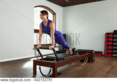 The Instructor Does Exercises On The Reformer, A Beautiful Girl Trains On The Modern Reformer Simula