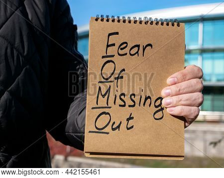Man Holds Page With Words Fomo Fear Of Missing Out.