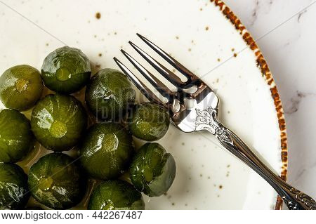 Top View Of Preserved Whole Green Figs And Dessert Fork On A White Porcelain Plate. Sweet Jam Of Unr
