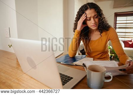 Stressed Multi-cultural Female Trying To Understand Bills. Young Professional Remote Working With La