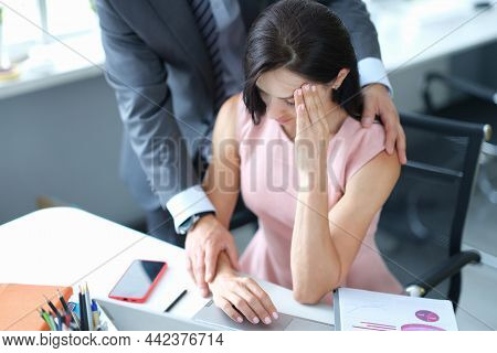 Businessman Hugs Embarrassed Employee In Office. Sexual Harassment At Work Concept