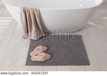 Soft Grey Bath Mat And Slippers On Floor In Bathroom