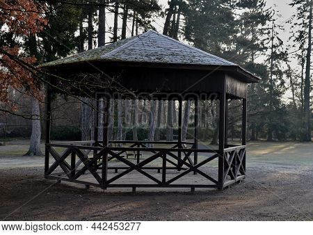 Polygonal Pergola With Benches And A Fence Around The Perimeter. There Is A Lot Of Space Inside. The