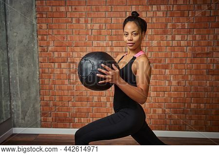 Side Portrait Of An Attractive Muscular Build Woman In Stylish Black Sportswear, Exercising With Med