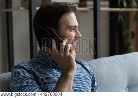 Man Sitting On Couch In Living Room Talking On Cellphone