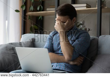 Upset Man Sit On Sofa With Laptop