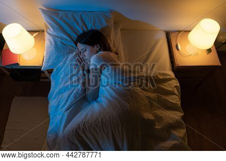 Top View Of A Beautiful Girl Sleeping Cozily On A Bed In Her Night Room With Blue Colors From The Mo