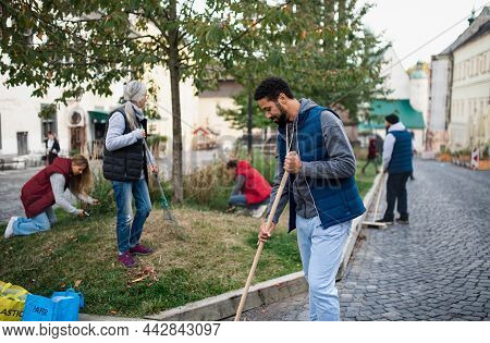 Young Man Volunteer With Team Cleaning Up Street, Community Service Concept