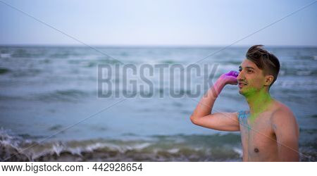 A Young Guy Throws Colour Powder Against The Background Of The Sea