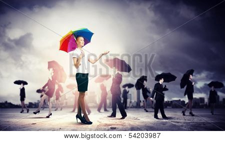 Image of pretty businesswoman with umbrella walking in crowd of people