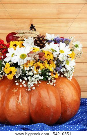 Beautiful autumn composition in pumpkin on table on wooden background
