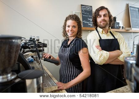 Portrait of confident workers standing at counter in coffeeshop