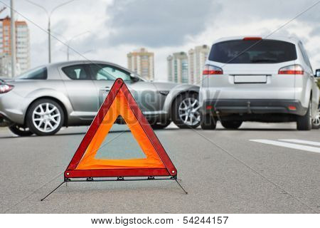 Car collision in city street. Road warning triangle sign at first plane