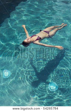 Girl Floating In Swimming Pool
