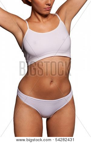 Close up view of the midriff torso of an athletic woman in a white sports bra and panties with a shapely curvy figure posing with her arms raised isolated on white