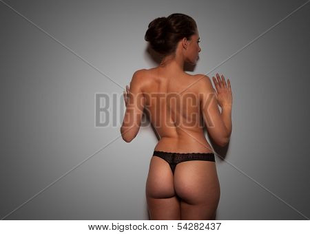 Close up view of the shapely curvaceous body of a sexy tanned young woman in black lingerie standing with her hands to her hips, torso view on white