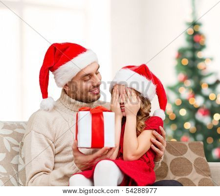 family, christmas, x-mas, winter, happiness and people concept - smiling daughter with closed eyes waiting for a present from fathe