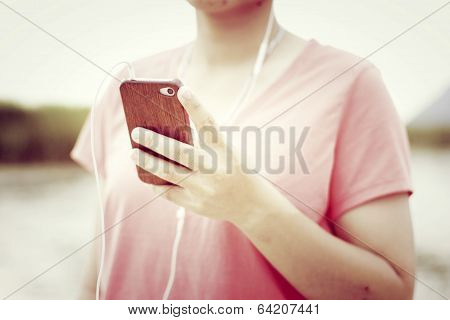 Woman holding a smartphone listening to music with retro filter effect
