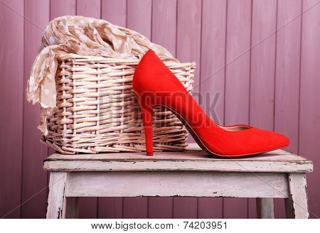 Red women shoes and scarf on bench on wooden background