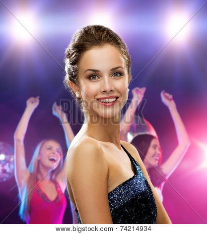 holidays, party and people concept - smiling woman in evening dress over disco background