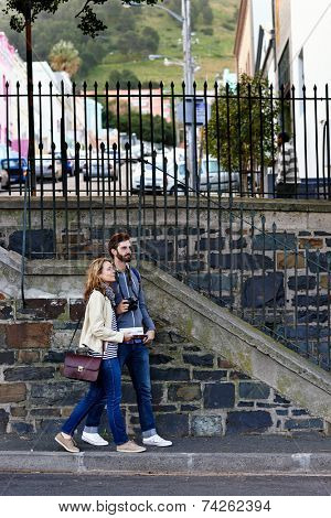 travel couple walking around city on vacation with guide book having fun