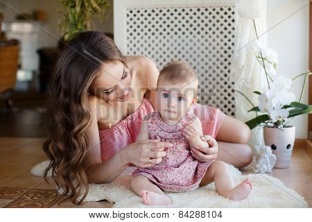 Happy mother and baby daughter playing and having fun at home.