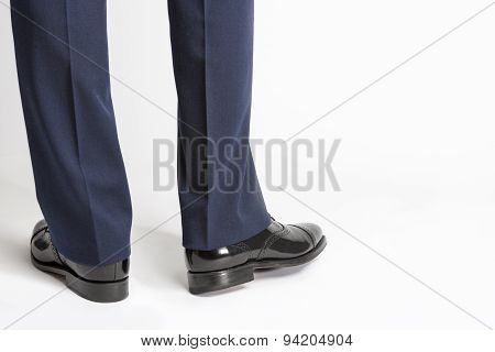 Man In Stylish Black Shiny Male Semi-brogue Posing In Reversed Position Against White.