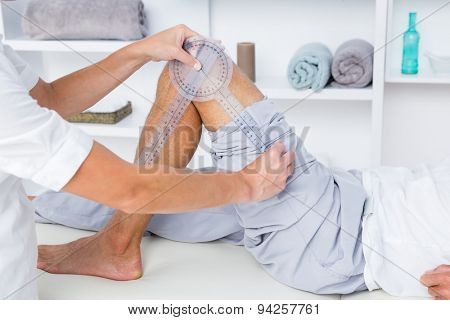 Doctor examining man leg with tool in medical office