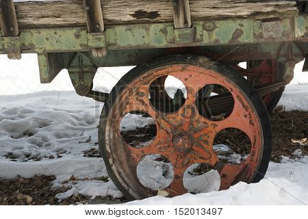 A wheel of an antique hay wagon in the snow