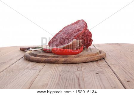 fresh raw beef meat steak chunk with red hot pepper on wood with stainless steel knife