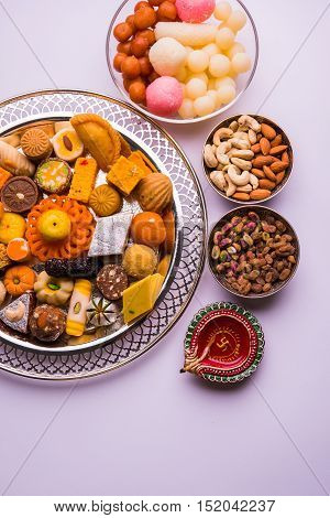 Mix Mithai and diya on diwali over colourful background