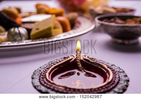 Mix Mithai and diya on diwali over colourful background