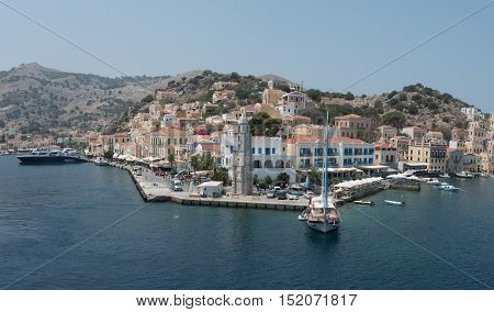 Symi Greece - August 1 2016: Panoramic image of Symi town with the harbor and luxury yachts in the Greek Island of Symi at the Aegean sea.