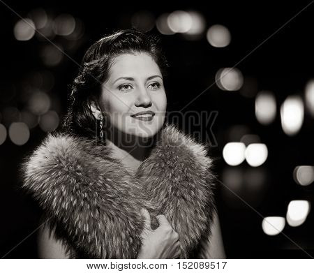 woman studio portrait in hollywood style light with night lights background. black and white variation