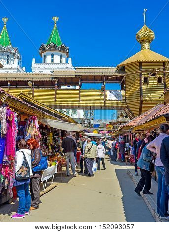 MOSCOW RUSSIA - MAY 10 2015: The crowded souvenir row of Izmailovsky Market with the timbered church and covered gallery on the background on May 10 in Moscow.