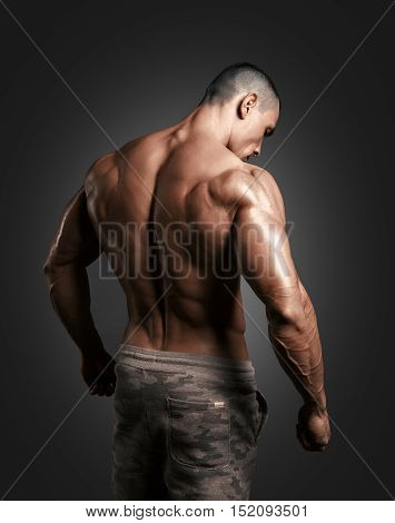 Bodybuilder showing his back and biceps muscles, personal fitness trainer. Strong man flexing his muscles