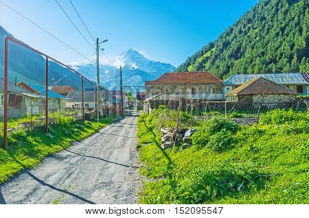 The snowy Kazbek Mount rises over the houses of Akhaltsikhe village in Sno valley Kazbegi Georgia.